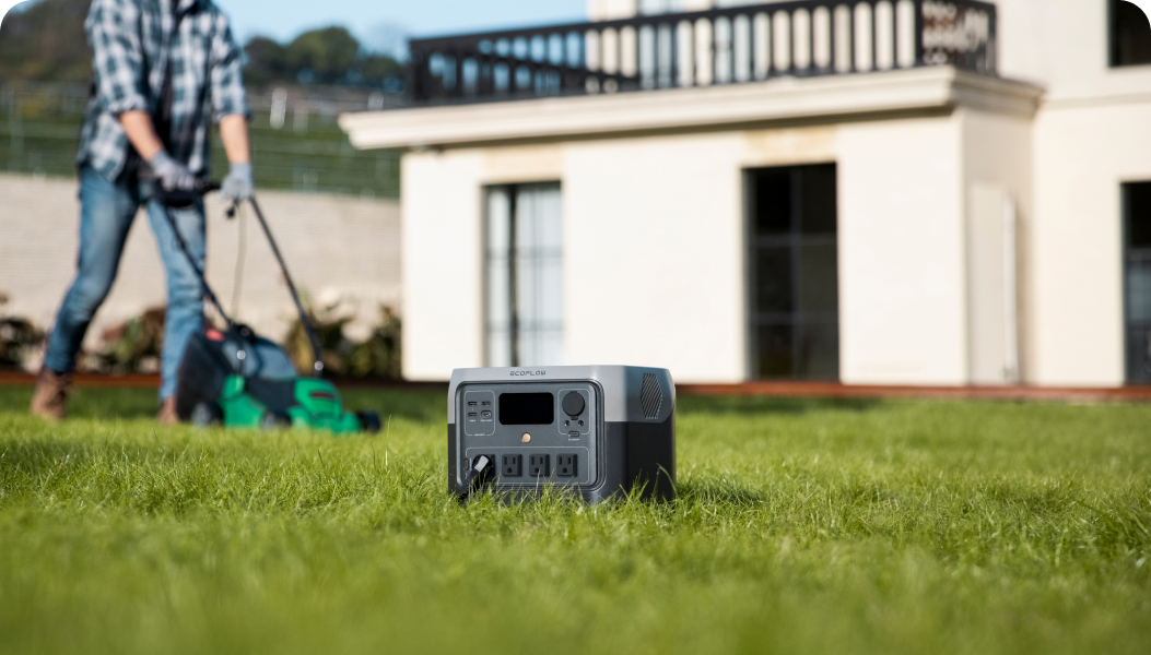 EcoFlow RIVER 2 Pro sits on the grass while a man mows in the background.